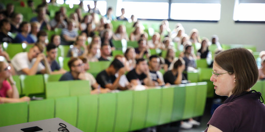Lecturer sits in front of students in the lecture hall in the seminar building.